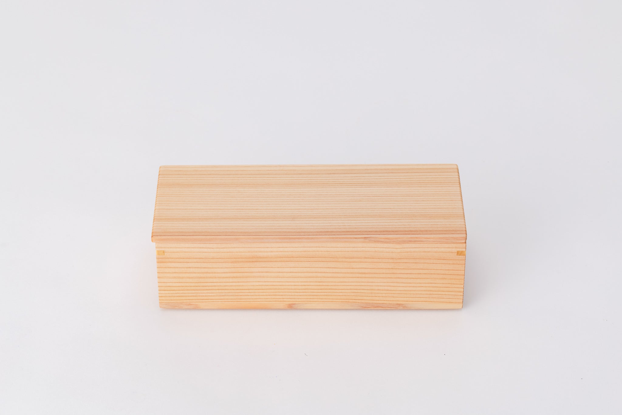 A rectangular box made of light-colored cedar sits on a white background with its lid closed. The long edge of the box faces the viewer.